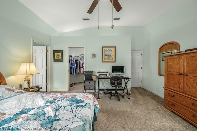 carpeted bedroom featuring a walk in closet, a closet, vaulted ceiling, and ceiling fan