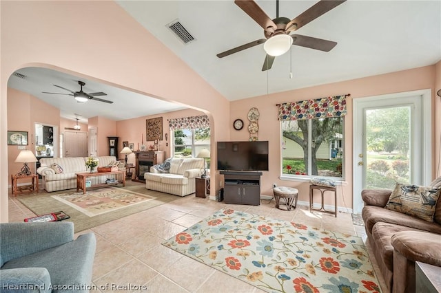 living room featuring ceiling fan, a fireplace, light tile patterned flooring, and lofted ceiling