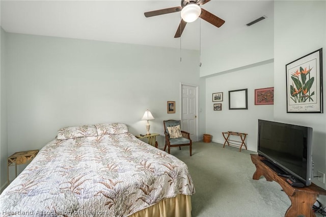 bedroom with carpet, ceiling fan, and a towering ceiling