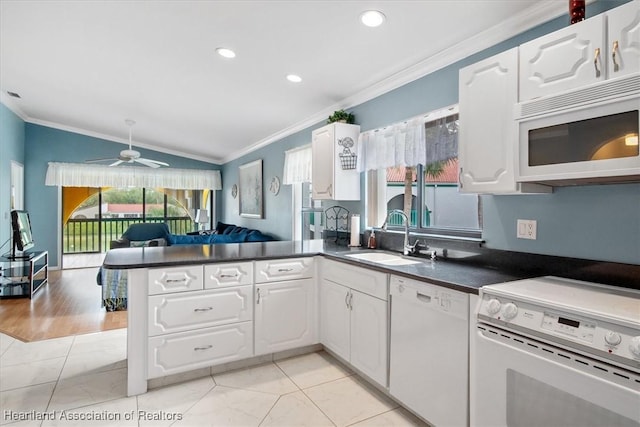 kitchen with kitchen peninsula, white appliances, sink, white cabinetry, and lofted ceiling