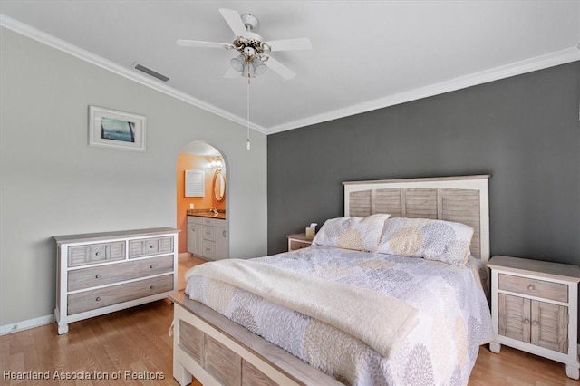 bedroom with connected bathroom, ceiling fan, wood-type flooring, vaulted ceiling, and ornamental molding