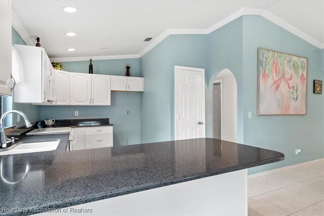 kitchen with lofted ceiling, sink, kitchen peninsula, ornamental molding, and white cabinetry