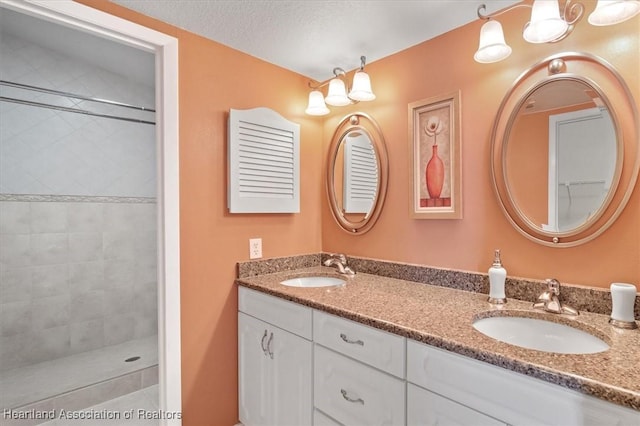 bathroom with vanity, a textured ceiling, and tiled shower