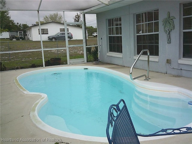 outdoor pool with glass enclosure and a patio area