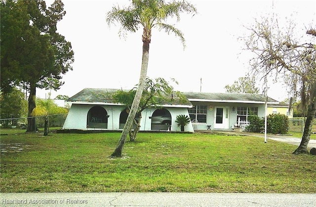 ranch-style home with stucco siding, fence, and a front lawn