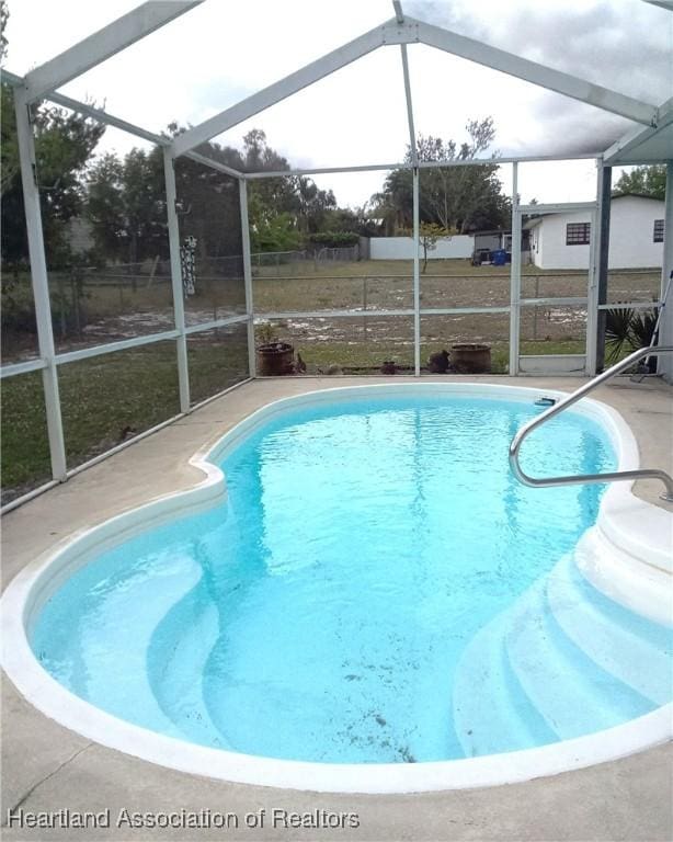 outdoor pool featuring glass enclosure and a patio area