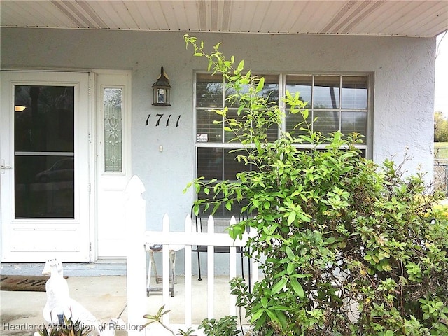 property entrance featuring stucco siding and a porch