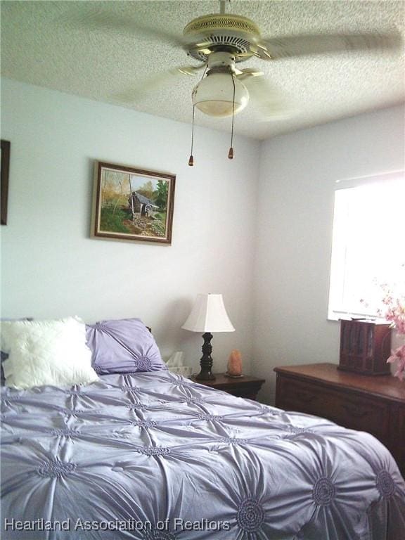 bedroom with a textured ceiling and a ceiling fan