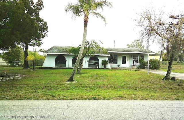 ranch-style home with stucco siding, fence, and a front yard