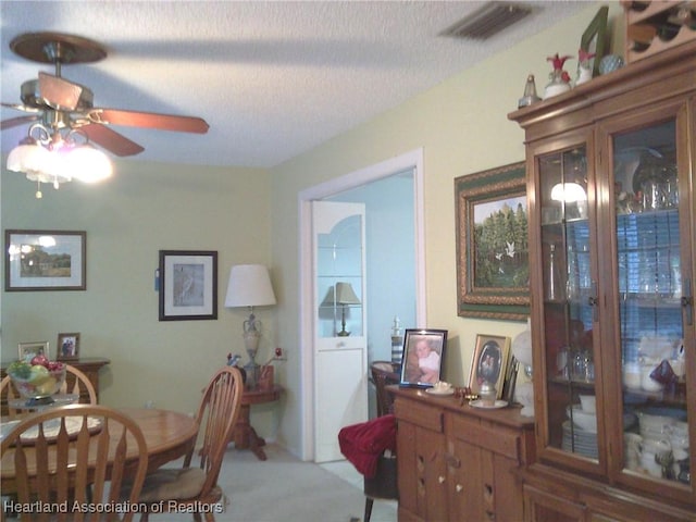 dining area featuring visible vents, a textured ceiling, and a ceiling fan