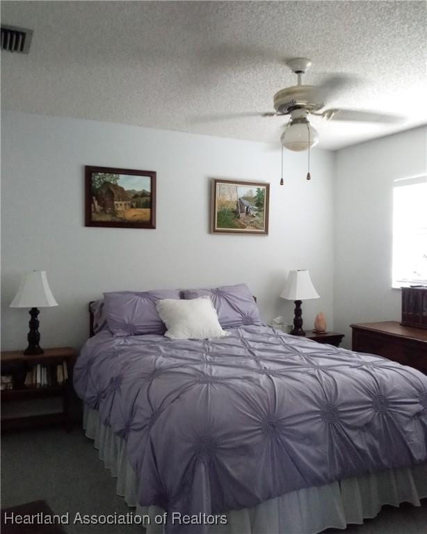 bedroom with a textured ceiling, ceiling fan, and visible vents