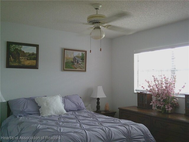 bedroom with a textured ceiling and a ceiling fan