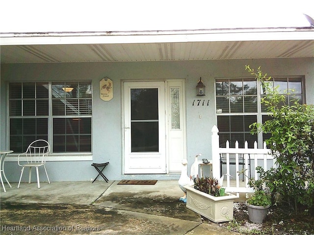 doorway to property featuring stucco siding and covered porch