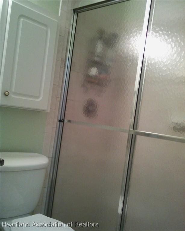 bathroom featuring a stall shower and toilet