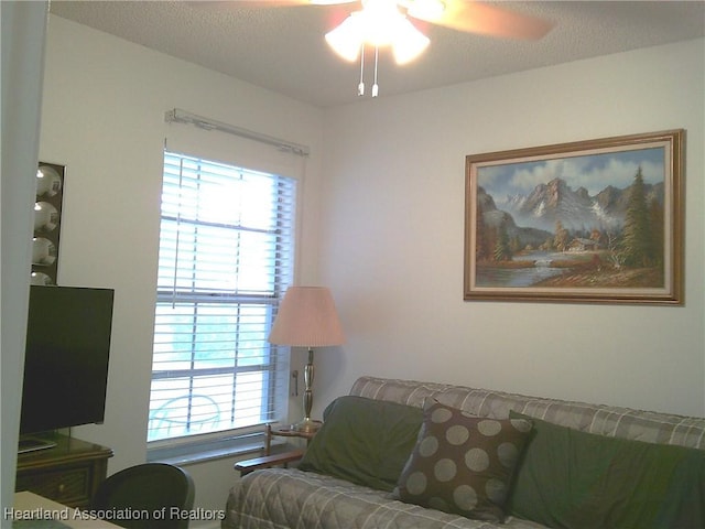 living room with a textured ceiling and a ceiling fan