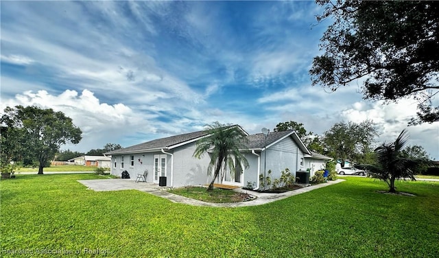 view of side of property with a lawn, central AC, and a patio