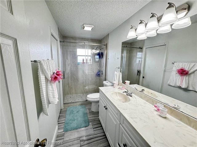 bathroom with vanity, toilet, an enclosed shower, and a textured ceiling