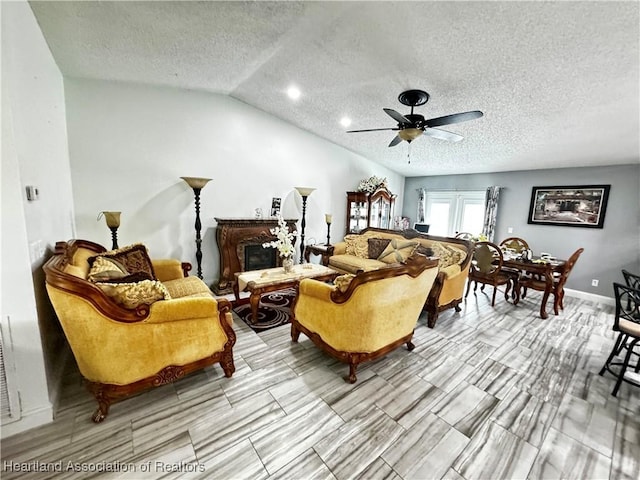 living room featuring ceiling fan, lofted ceiling, and a textured ceiling