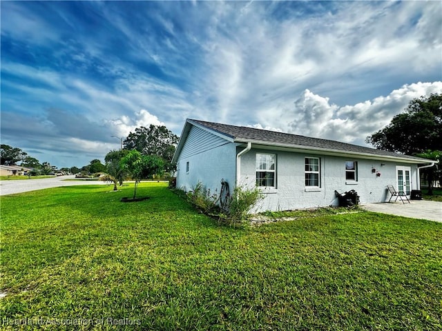 view of property exterior with a lawn and a patio area