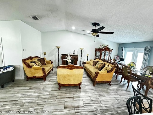 living room featuring ceiling fan, lofted ceiling, and a textured ceiling