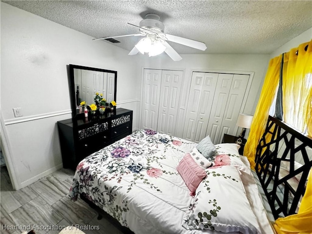 bedroom with a textured ceiling, ceiling fan, and multiple closets