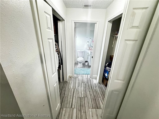 corridor featuring light hardwood / wood-style flooring and a textured ceiling