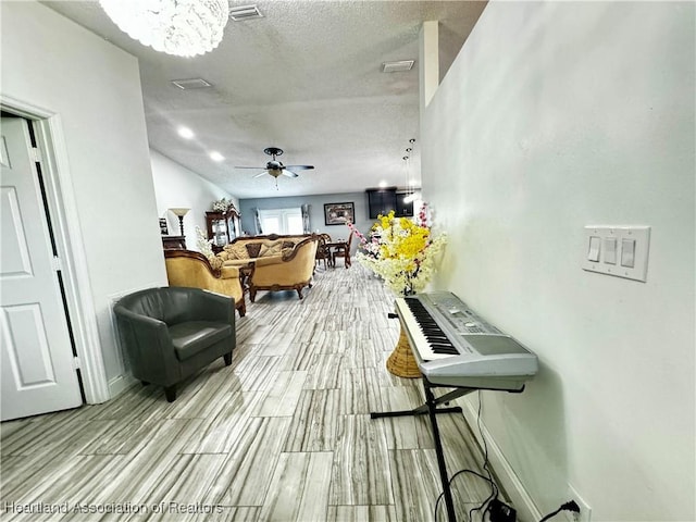 interior space featuring a textured ceiling, light hardwood / wood-style floors, and ceiling fan with notable chandelier