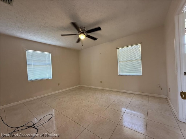 unfurnished room with visible vents, light tile patterned flooring, baseboards, a textured ceiling, and ceiling fan