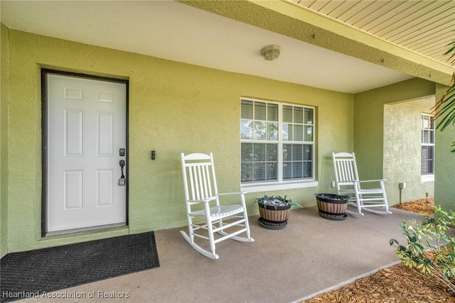 property entrance featuring a porch and stucco siding