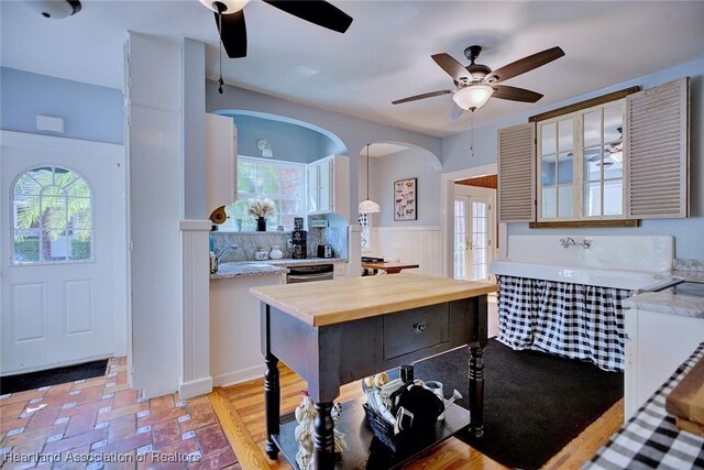 1237 Hotiyee Ave, Sebring, FL 33870 - kitchen with ceiling fan, arched walkways, wooden counters, a wainscoted wall, and plenty of natural light