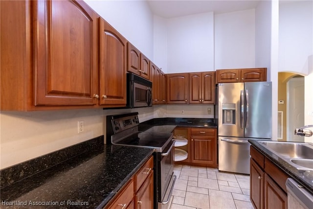 kitchen featuring black appliances, light tile patterned flooring, dark stone countertops, and sink