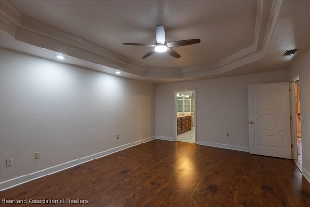 empty room featuring a tray ceiling, ceiling fan, dark hardwood / wood-style floors, and ornamental molding