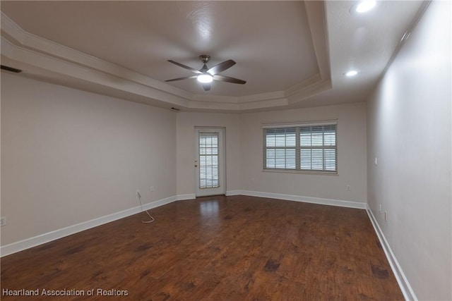 spare room with dark hardwood / wood-style flooring, a raised ceiling, and ceiling fan