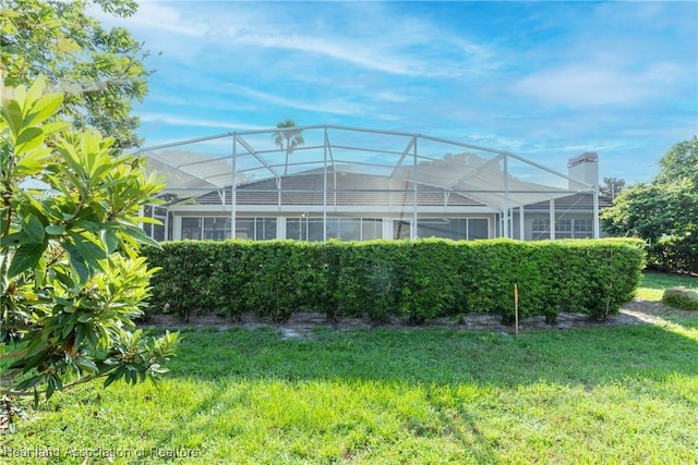 back of property with a lanai and a lawn