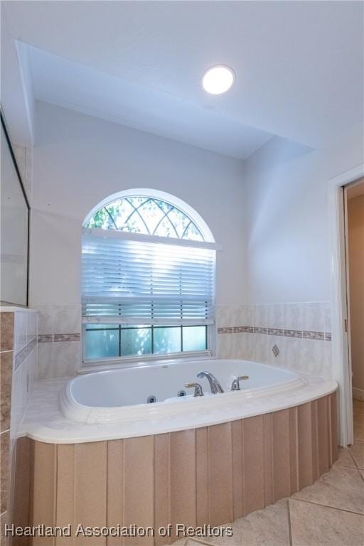 bathroom with tile patterned flooring, a wealth of natural light, and tiled bath