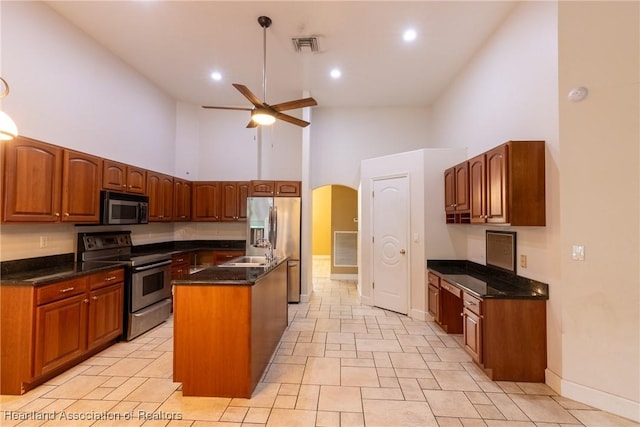 kitchen featuring stainless steel appliances, ceiling fan, sink, a high ceiling, and a kitchen island