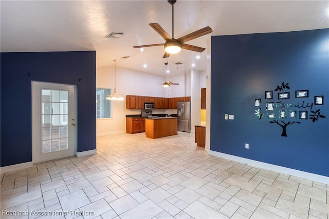 kitchen with stainless steel appliances, pendant lighting, vaulted ceiling, a kitchen island, and ceiling fan with notable chandelier