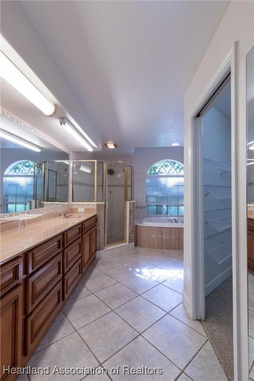 bathroom with plus walk in shower, vanity, tile patterned floors, and plenty of natural light