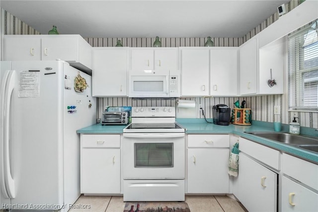 kitchen with white appliances, white cabinetry, and light tile patterned flooring