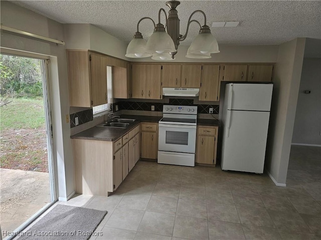 kitchen with dark countertops, backsplash, a sink, white appliances, and under cabinet range hood