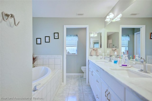 bathroom with tile patterned floors, tiled tub, vanity, and toilet