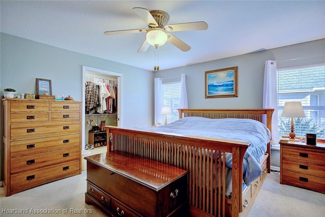 carpeted bedroom featuring a walk in closet, a closet, and ceiling fan