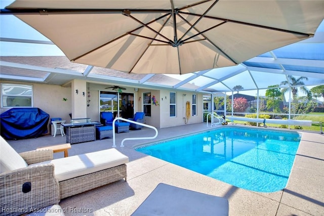 view of pool with outdoor lounge area, ceiling fan, glass enclosure, grilling area, and a patio area