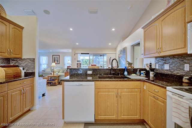 kitchen with white appliances, sink, dark stone counters, and vaulted ceiling