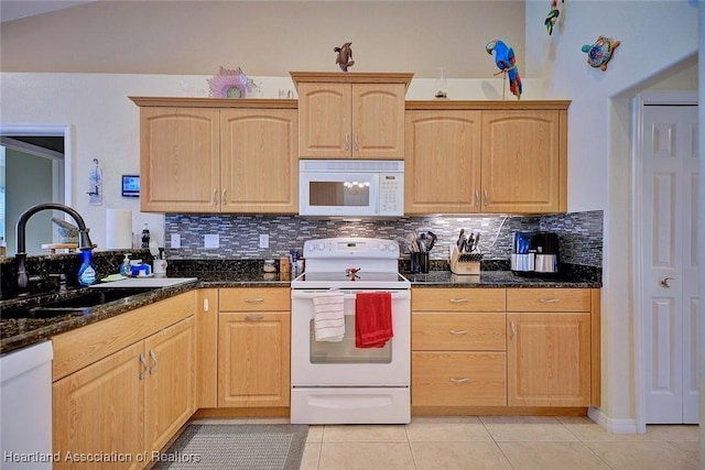 kitchen featuring white appliances, sink, light brown cabinets, dark stone countertops, and light tile patterned flooring