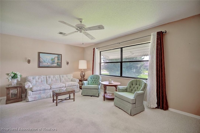 living room featuring carpet flooring, ceiling fan, and a textured ceiling