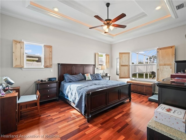 bedroom with crown molding, a tray ceiling, and dark hardwood / wood-style flooring