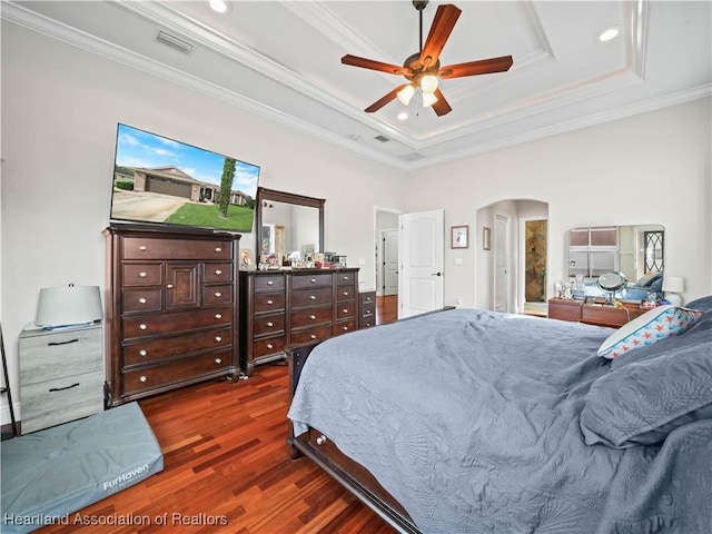 bedroom with ceiling fan, dark hardwood / wood-style floors, a tray ceiling, and ornamental molding