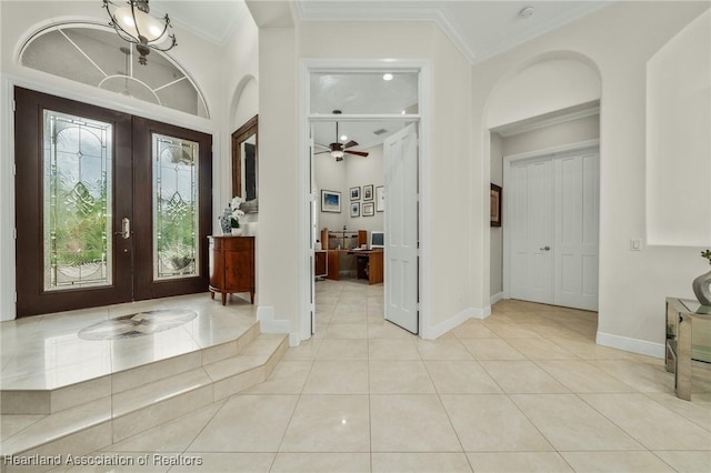 tiled entryway featuring ceiling fan with notable chandelier, crown molding, and french doors