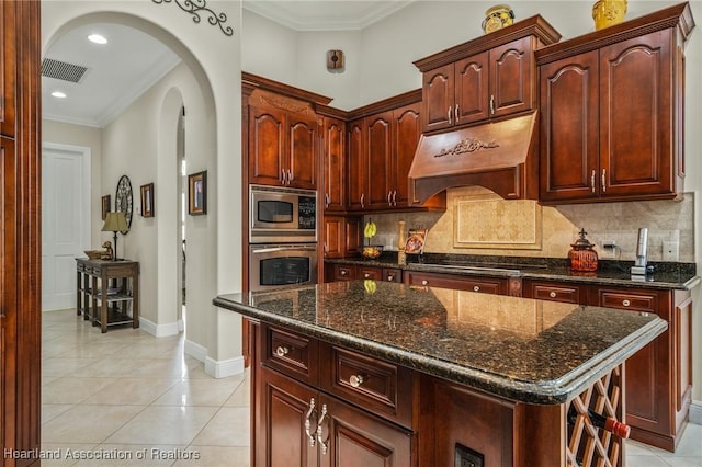 kitchen with backsplash, premium range hood, light tile patterned floors, a kitchen island, and stainless steel appliances